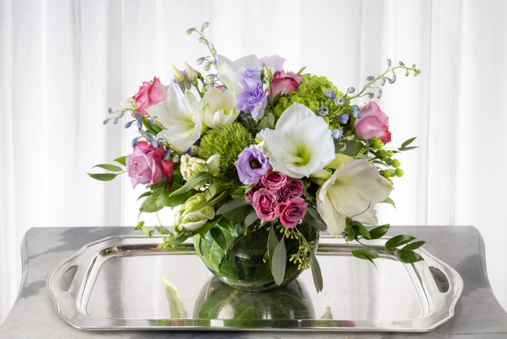Bright spring arrangement with fresh flowers with white, pink and lavender blossoms in an emerald leaf wrap.