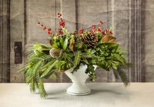A RWF Original fresh evergreen, succulent and berries arranged with magnolia in a pedestal urn.