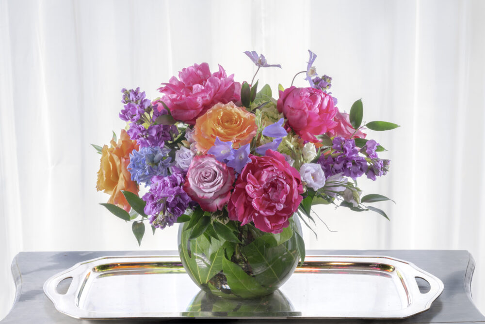 Gorgeous bright pink peonies and coral roses with accents in purple for a vibrant arrangement for Mother’s Day, delivered.
