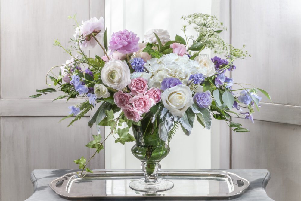 Stunning tall Mother’s Day design of pretty pink and white peonies and Ecuadoran roses in a tall pedestal vase.
