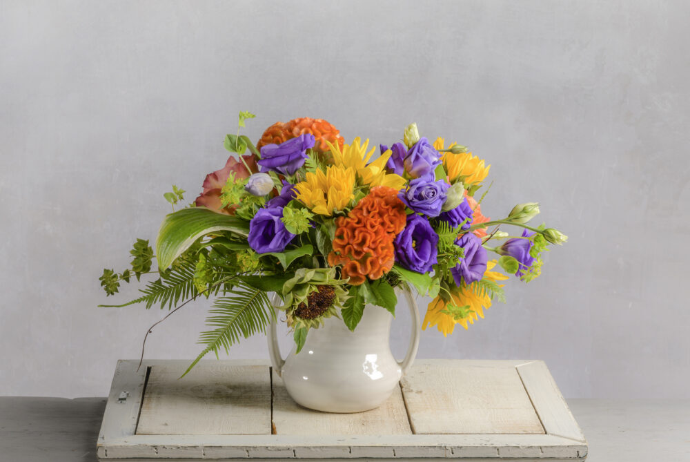 A charming bouquet of vibrant colorful summer field flowers in sunflower yellow, orange, and purple is a perfect ‘thank you’, delivered for you.