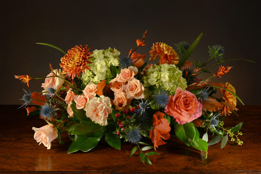 Fresh flowers and foliage Thanksgiving centerpiece with lush foliage and berries in bright fall colors.