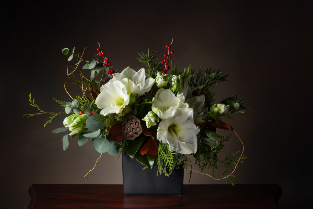 Winter Greens with magnolia, red winterberries, and bright white fresh flowers in a slim rectangle for taller design.