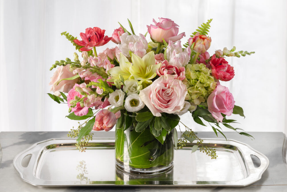 Lush and lovely Valentine flowers in pretty pinks and white wrapped in an emerald leaf-wrapped cylinder.