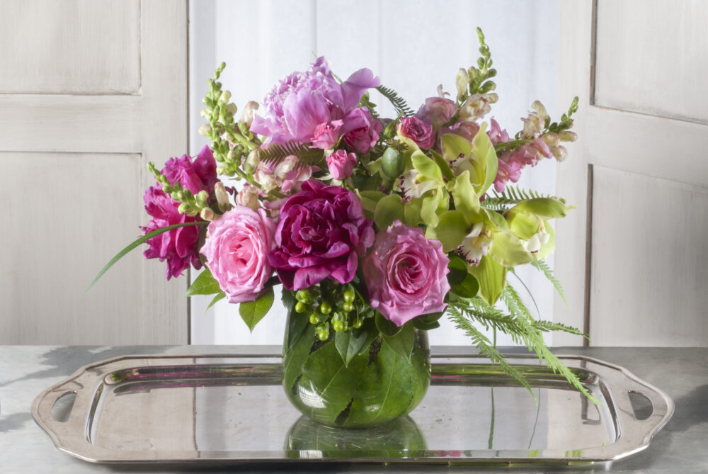 Lovely fresh pink peonies with bright green orchids in a leaf-wrapped cylinder, delivered.
