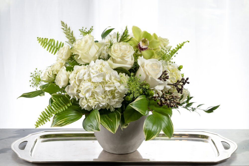 A unique, fresh bright green and crisp white summer flower arrangement with orchid accents designed in a smooth grey pot, delivered for you.