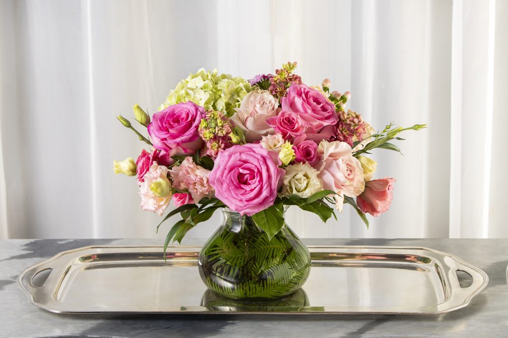 A sweet gift of a pretty pink bouquet-style fresh flower arrangement in an emerald leaf wrapped vase, delivered.