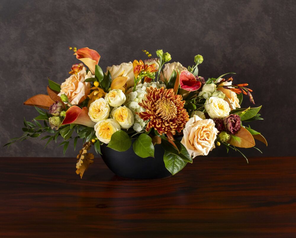 A creamy yellow, gold, peach, orange mix of autumn seasonal flowers in an oval ceramic vase, delivered, thanksgiving