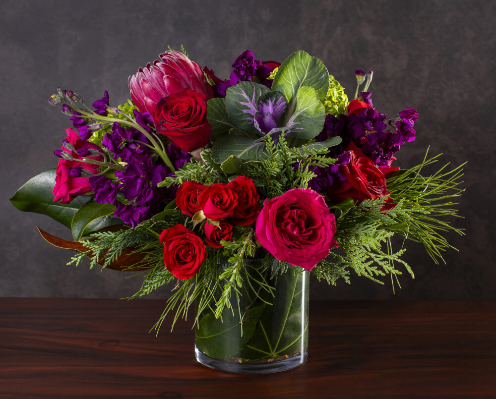 legant, bold, purple, pink, red, green, flower, arrangement with evergreen, magnolia in a glass vase with a leaf wrap delivered for holidays