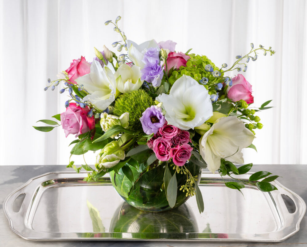 A bright, seasonal arrangement, amaryllis, flowers, greenery in a bubble vase, delivered, winter.