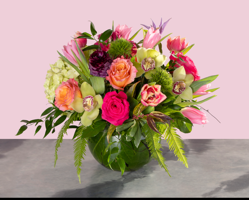Felicity is bright and unique spring arrangement of ranunculus, orchids, tulips, and roses in shades of green, coral, pink and purple.
