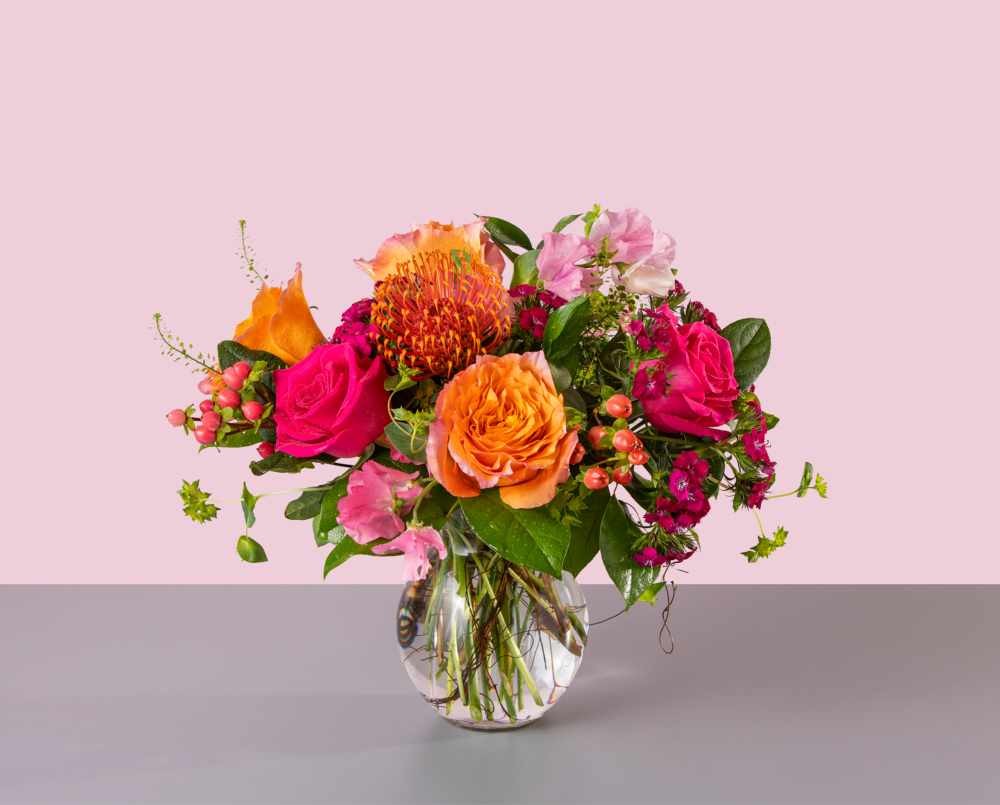 Julie is a vibrant pink and orange flower arrangement in a glass vase.