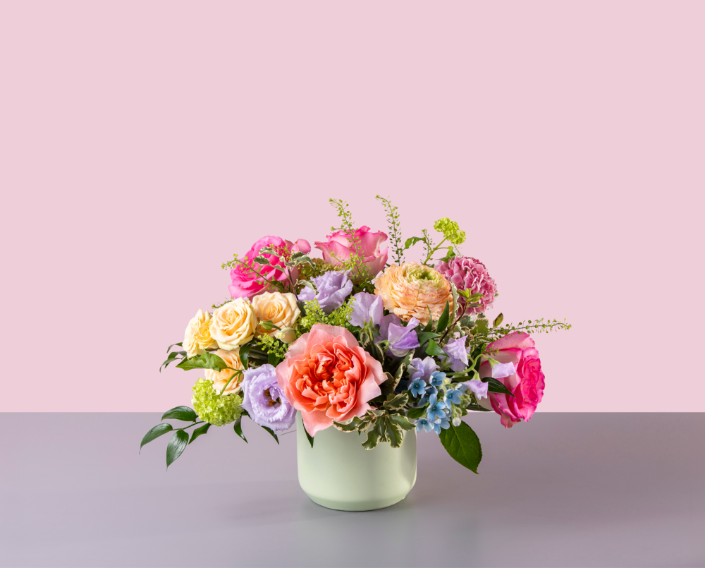 Luna is a pink, lavender, peach, blue arrangement in a light green ceramic vase.