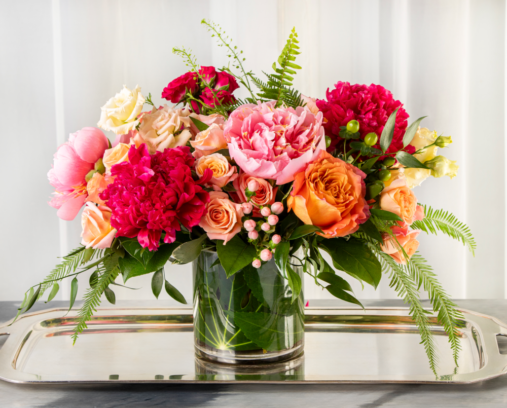 Ruby is a vibrant arrangement of peonies, roses and lisianthus in a clear glass vase.