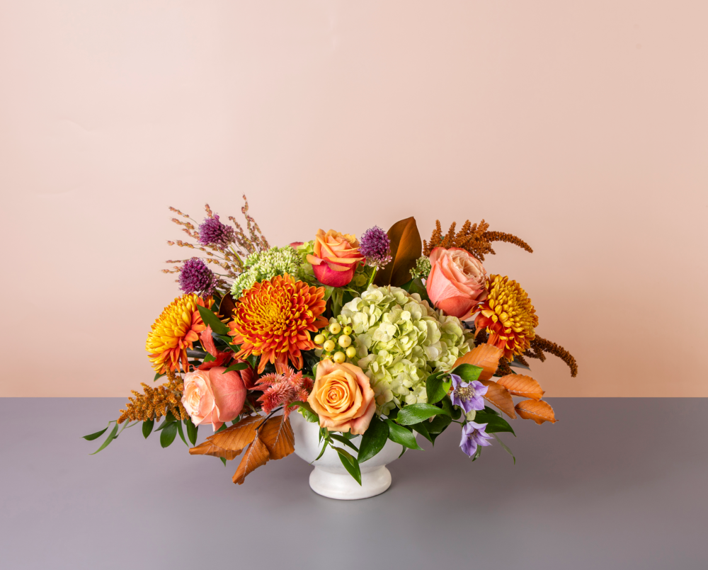 Birdie is a peach, green and lavender flower arrangement in a dawson pot.