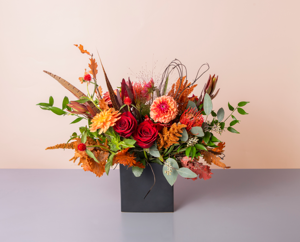 Curry is a bright red and orange flower arrangement in a black rectangular vase.