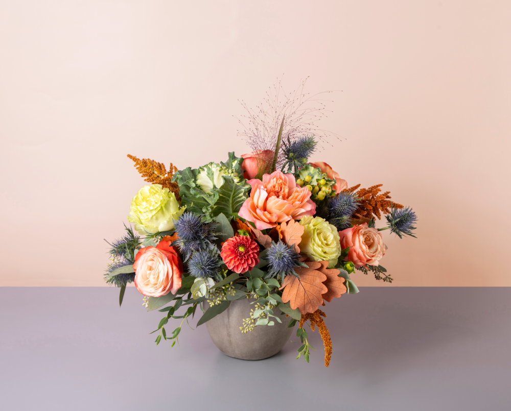 Gloria is a dusty fall arrangement with thistle, kale and fall leaves.