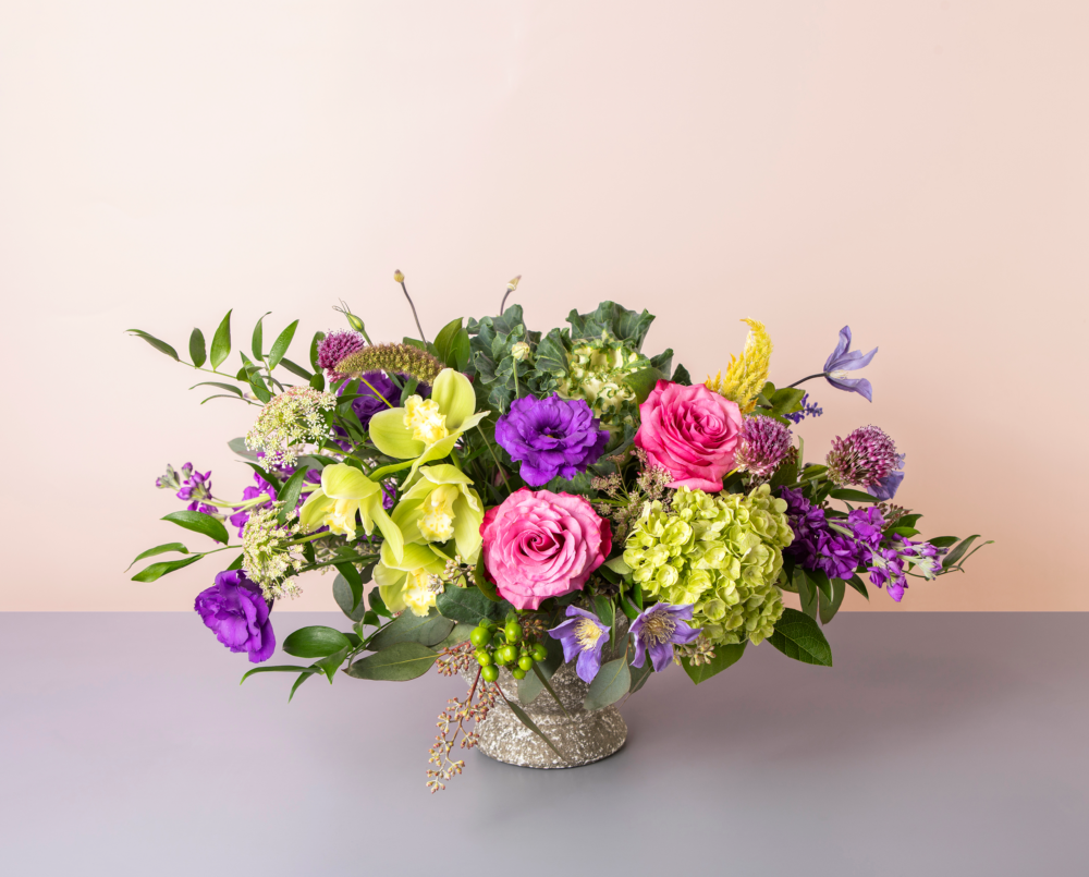 Vivian is a bright purple and green flower arrangement in a concrete pedestal vase.